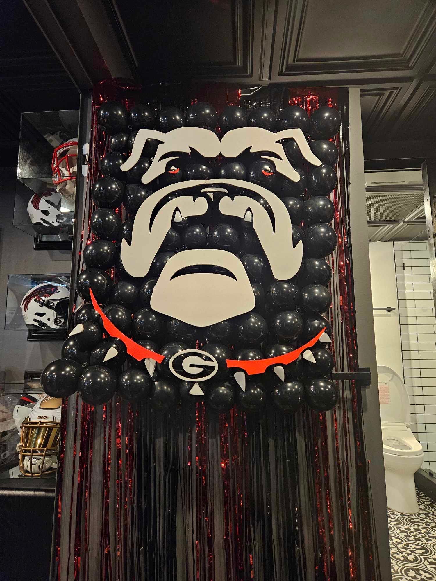 A picture of a bulldog made out of balloons is hanging on a wall.