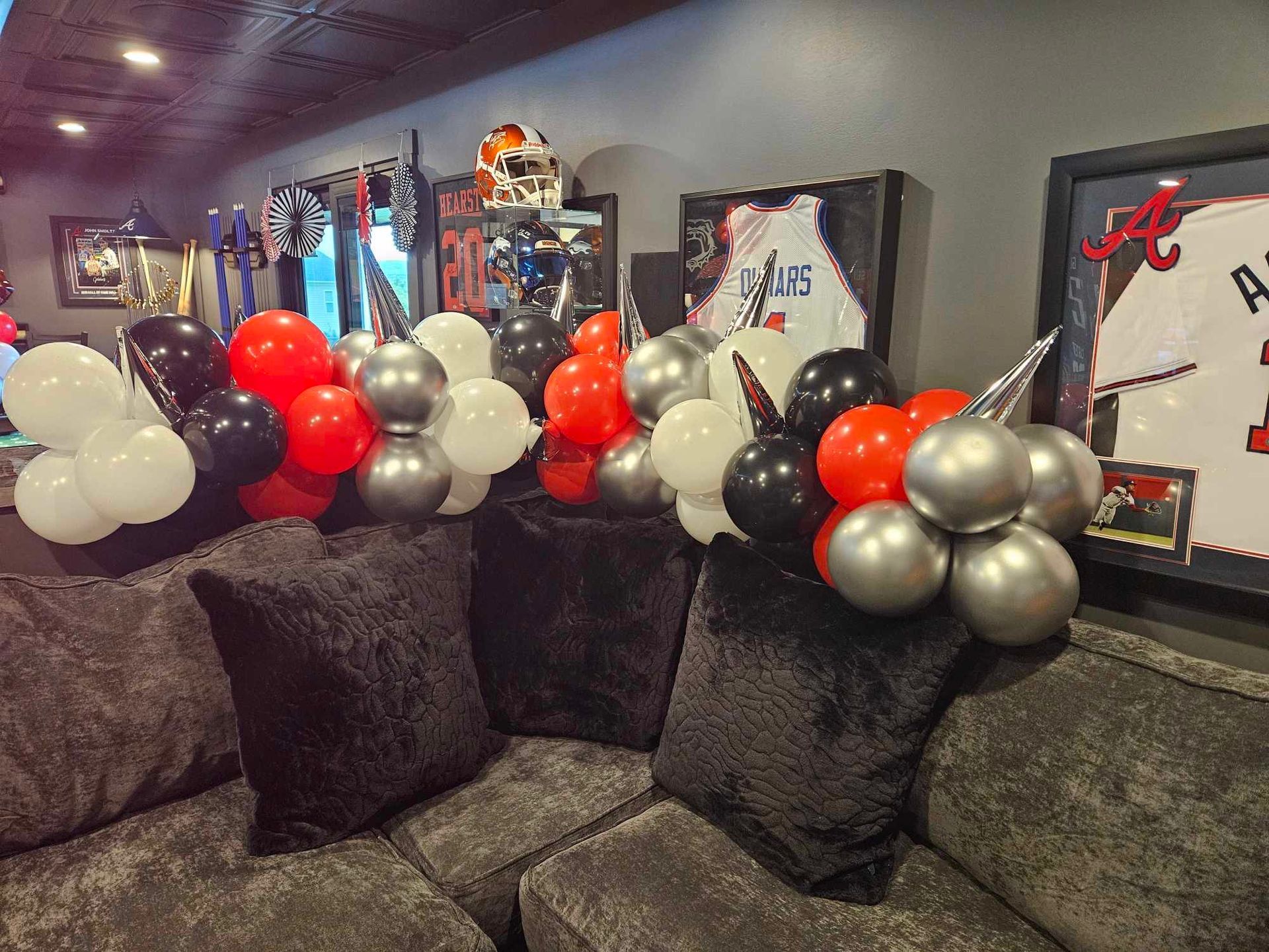 A couch with pillows and balloons on it in a living room.