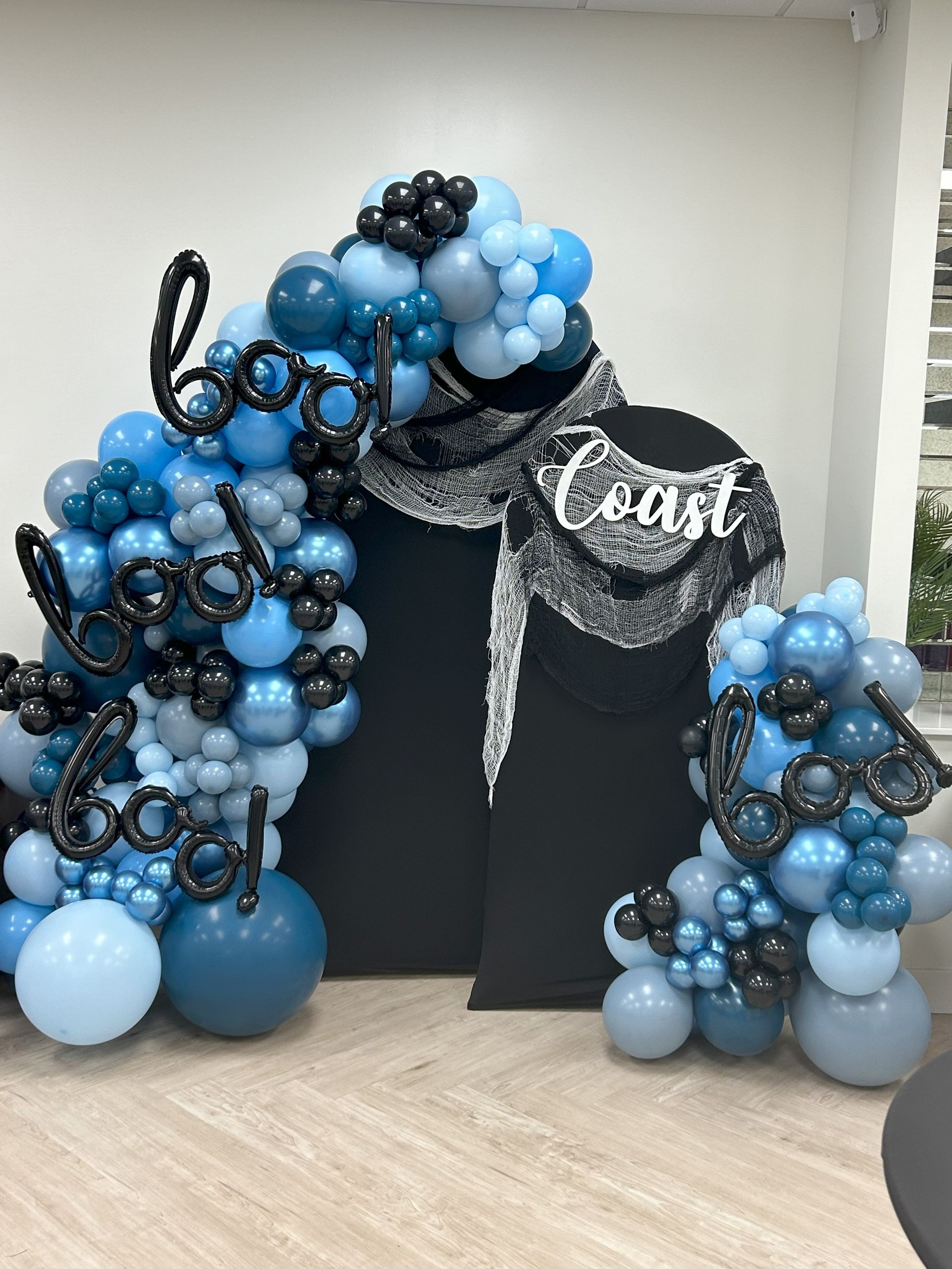 A bunch of blue and black balloons are sitting on a wooden floor.