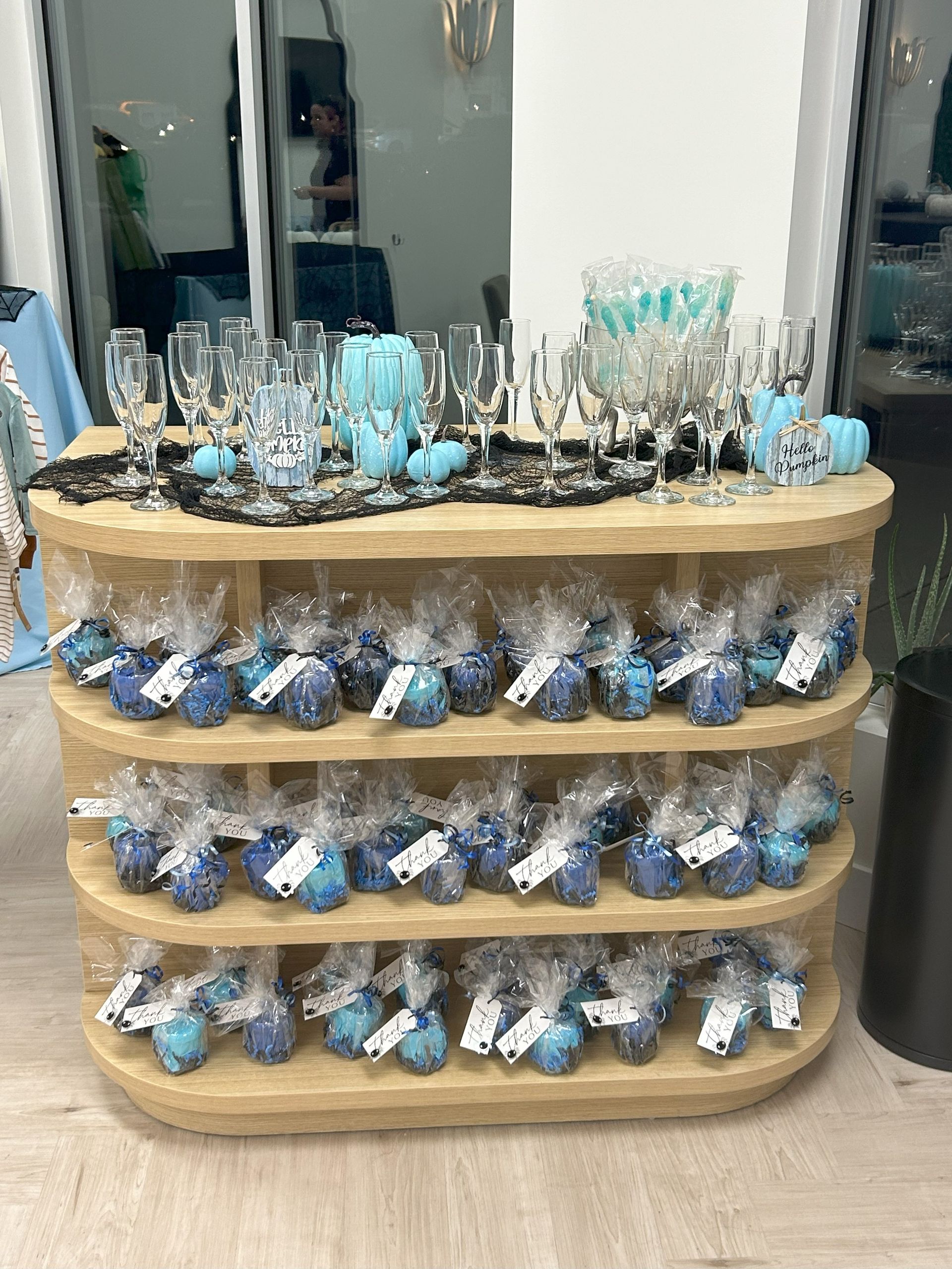 A wooden table filled with lots of blue treats and wine glasses.