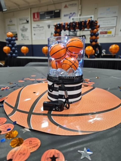 A glass filled with basketballs sits on a table