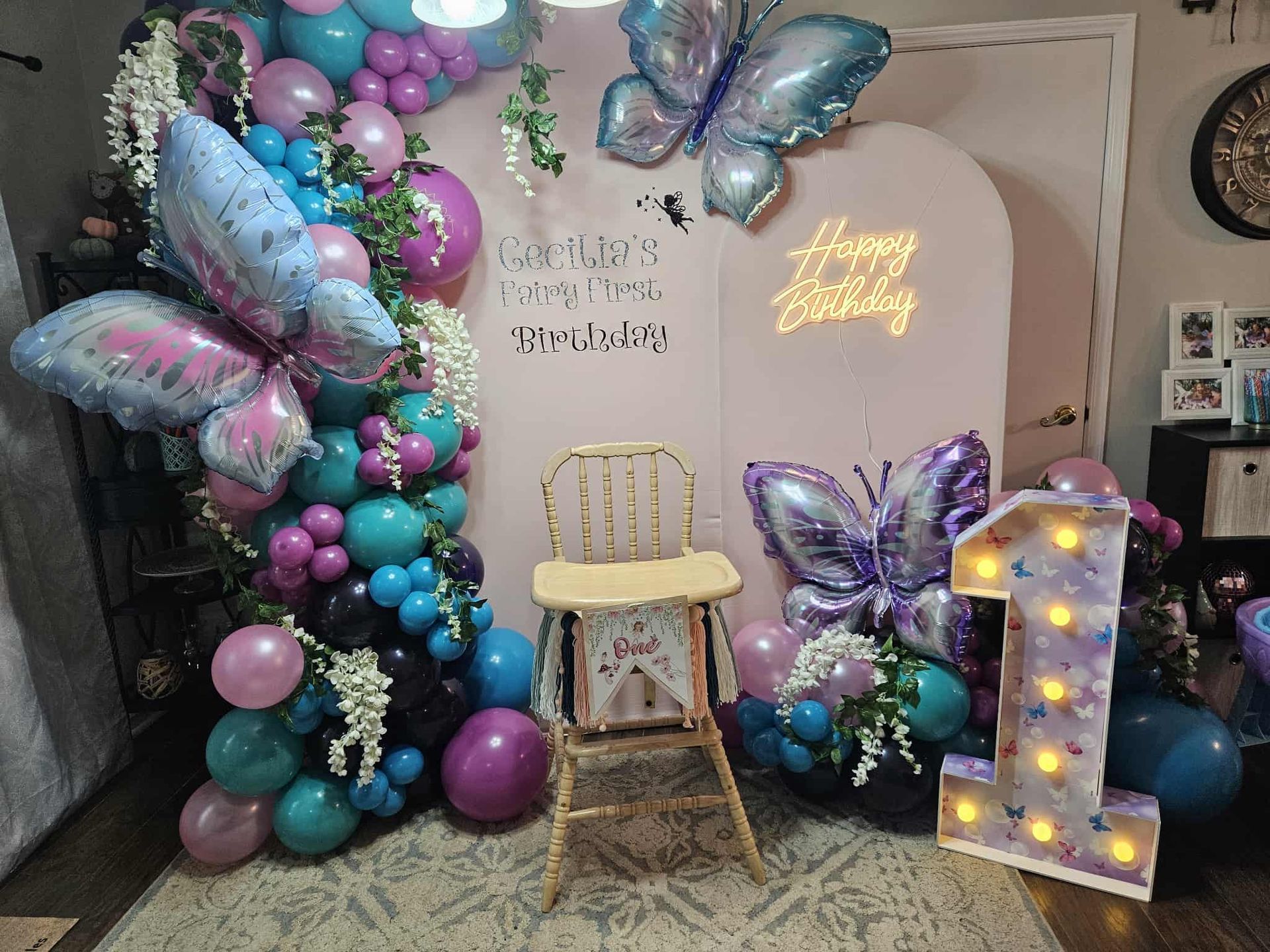 A room filled with balloons and a neon sign that says let 's party.