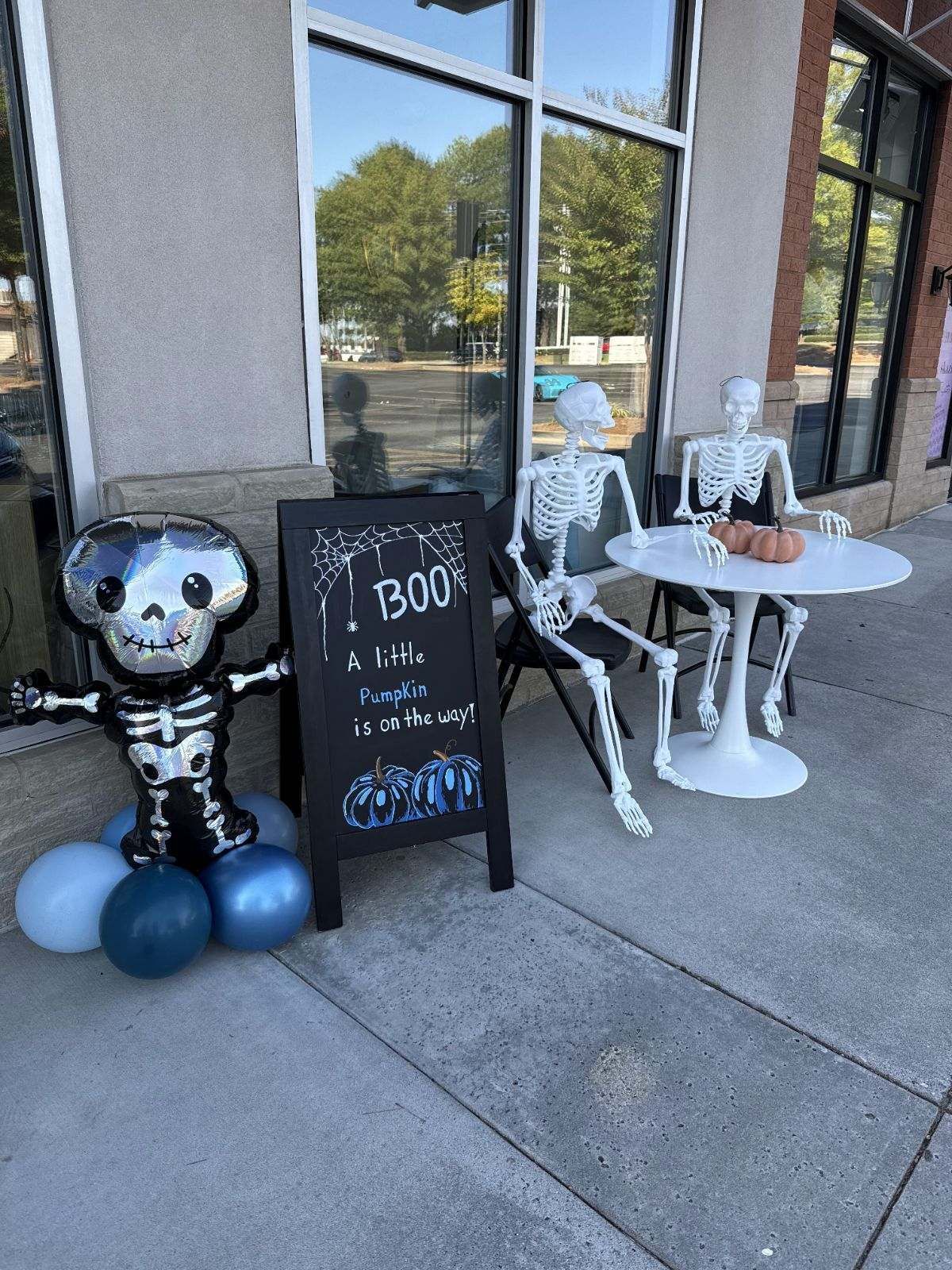 Two skeletons are sitting at a table in front of a building.