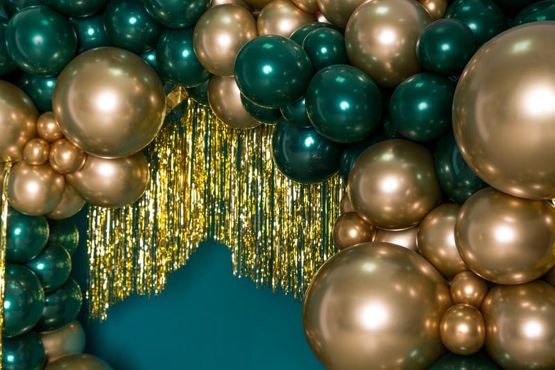 A bunch of gold and green balloons on a blue background.