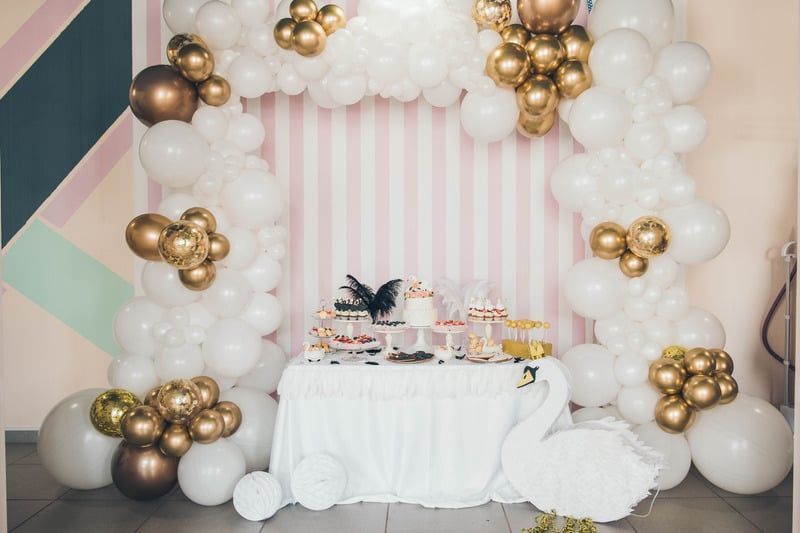 A table decorated with balloons and a swan for a birthday party.