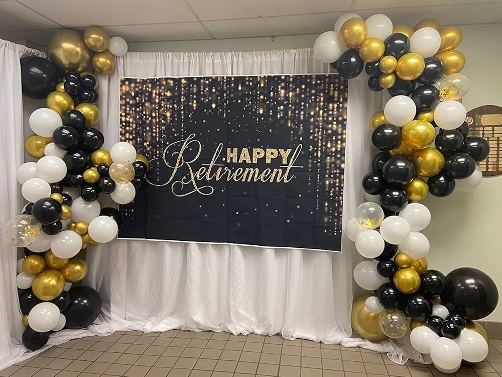 A room decorated with black , white and gold balloons for a happy retirement party.