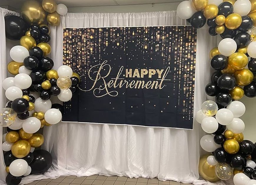 A happy retirement backdrop with black , white and gold balloons.