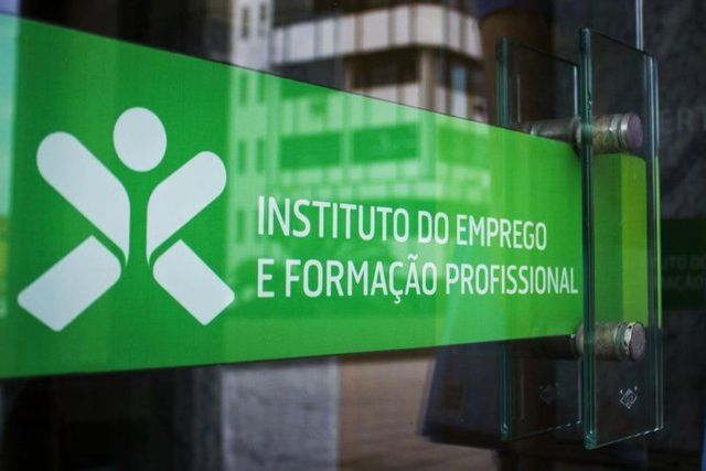 Green sign for the Instituto do Emprego e Formação Profissional with a stylized human figure logo, viewed through glass.