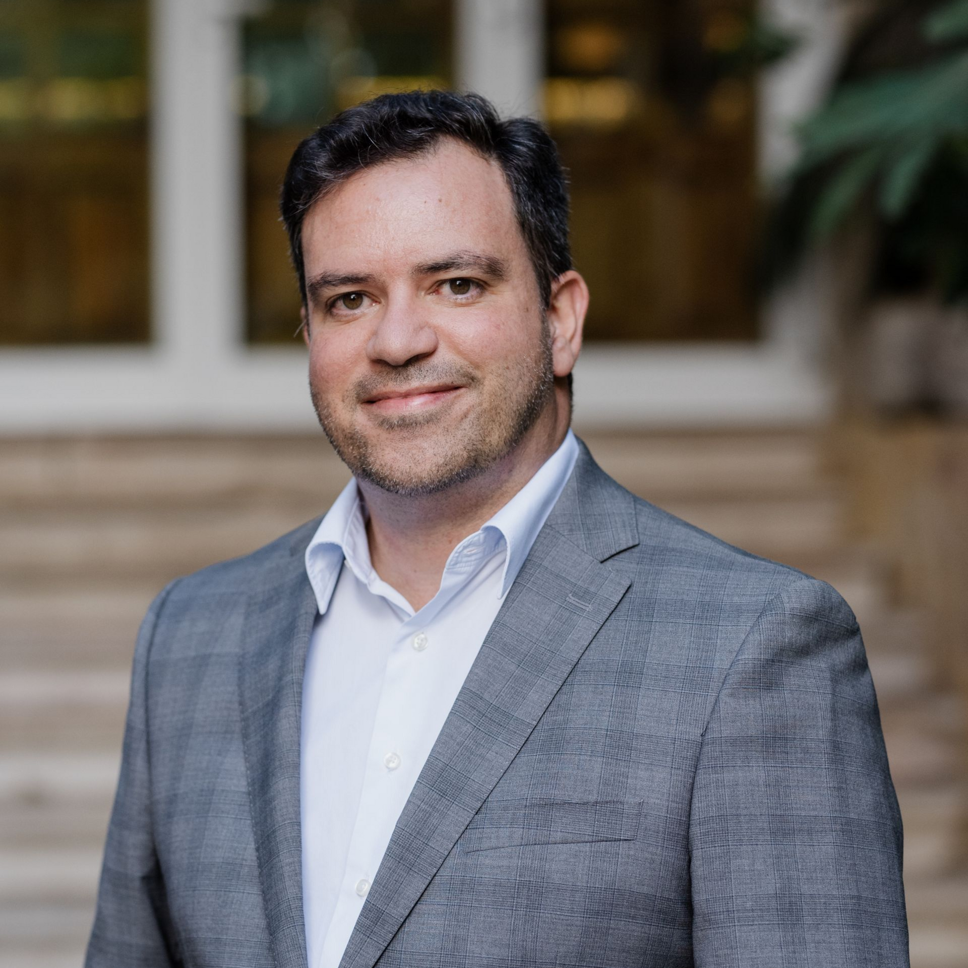 Dr. Nuno BravoUma pessoa de cabelos escuros e barba rala, vestindo um blazer cinza e uma camisa branca de botões, sorri em uma foto de rosto.