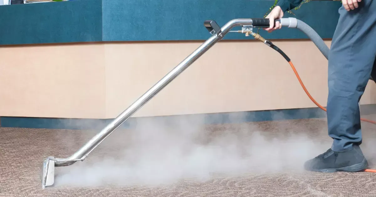 Technician using a professional machine for steam carpet cleaning in a commercial office space