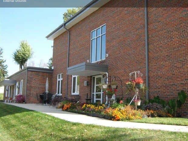 Red brick building with landscaped flower beds and green lawn.