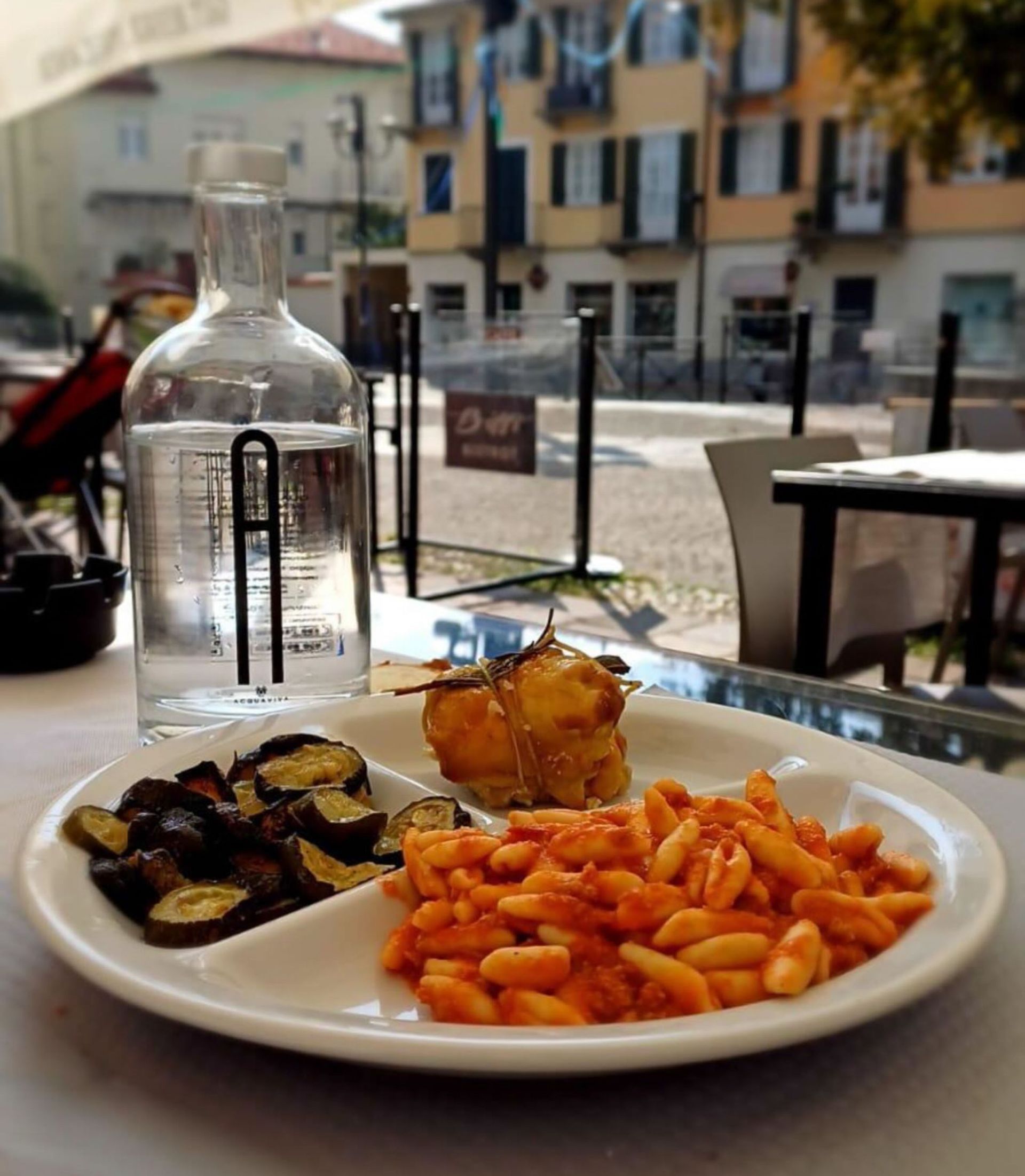 Un piatto di cibo con una bottiglia d'acqua sullo sfondo