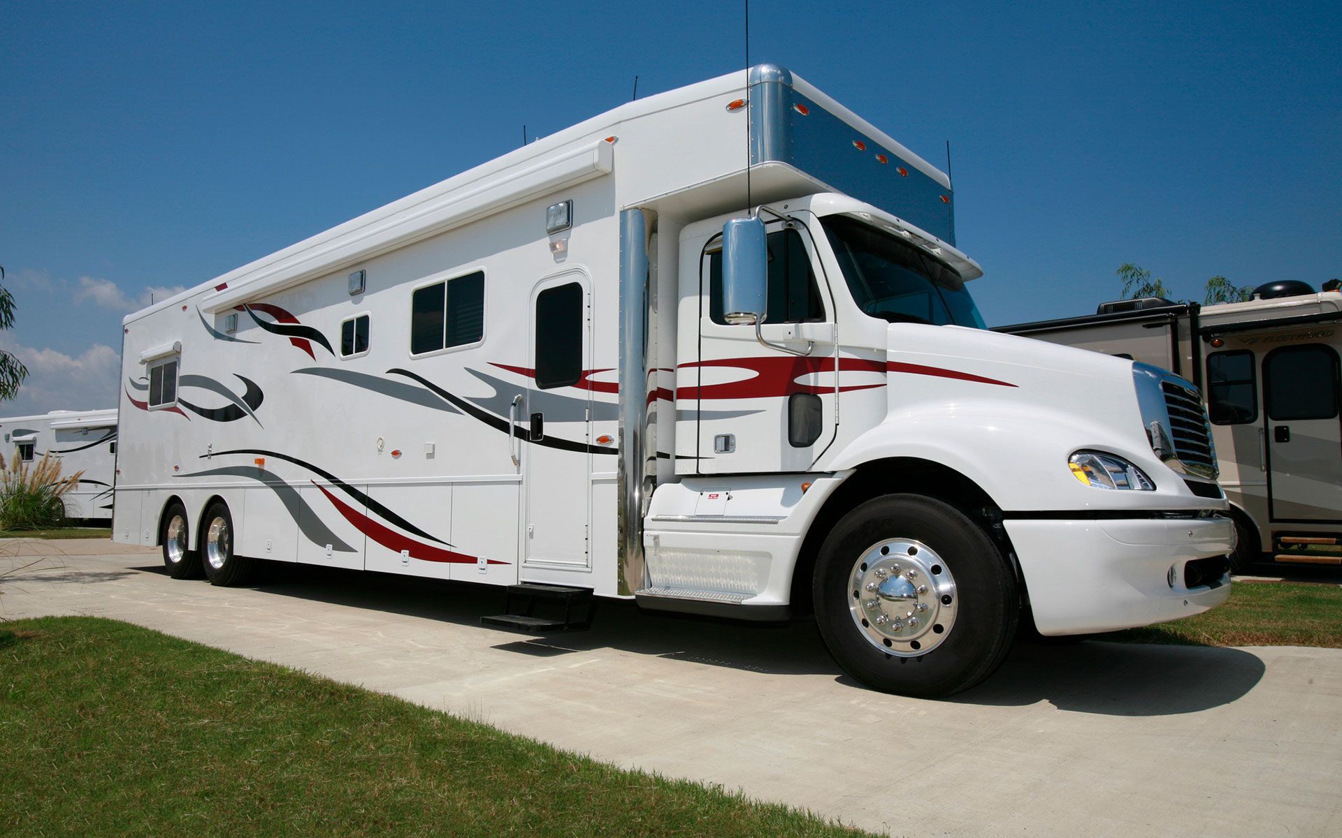 A large white rv is parked on the side of the road