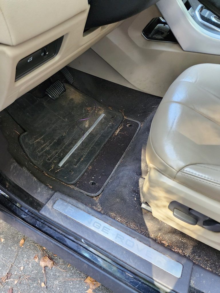 The inside of a dirty car with a dirty floor mat.