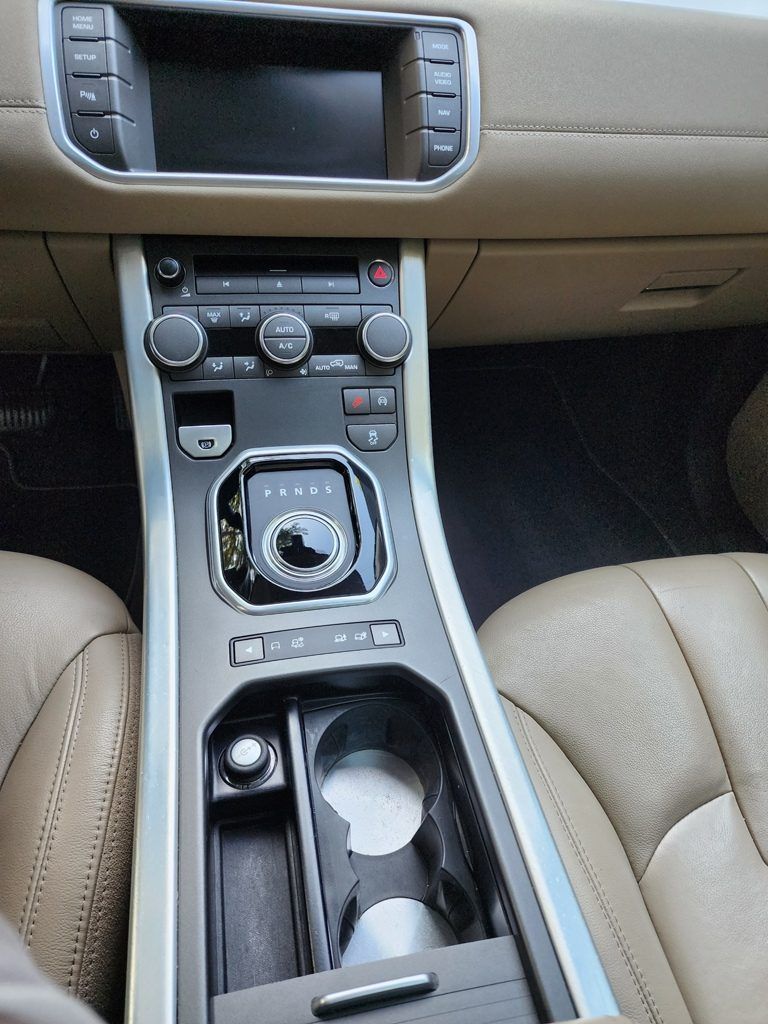 The dashboard of a car with a radio and a cup holder