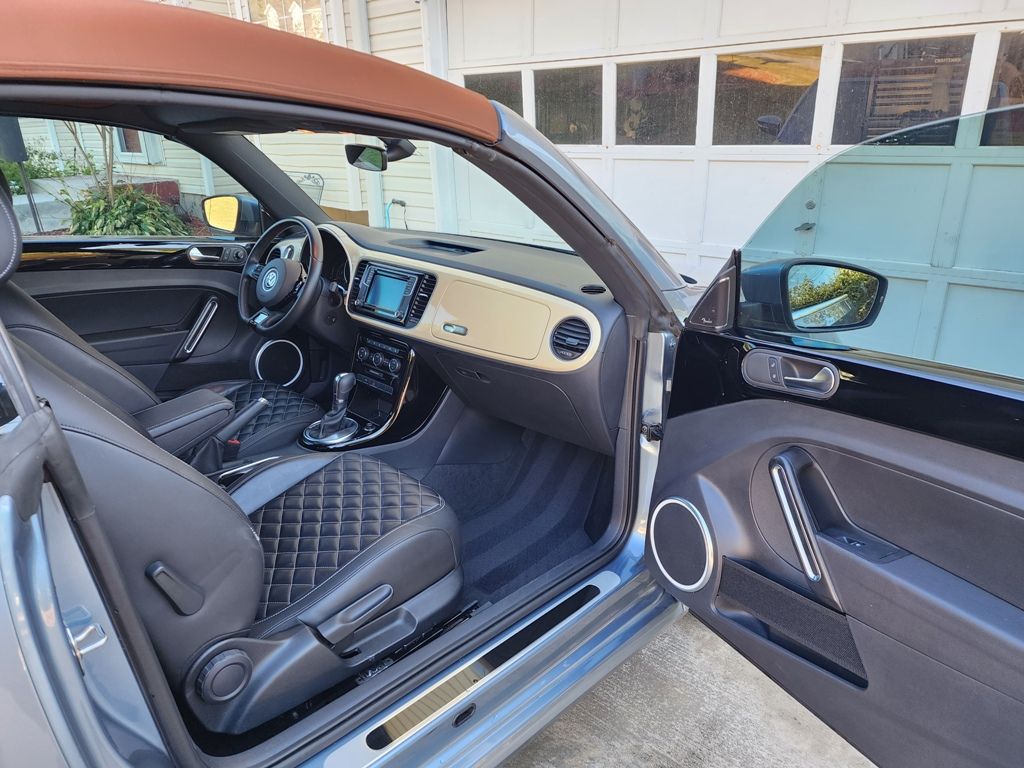 The interior of a volkswagen beetle convertible with the door open.