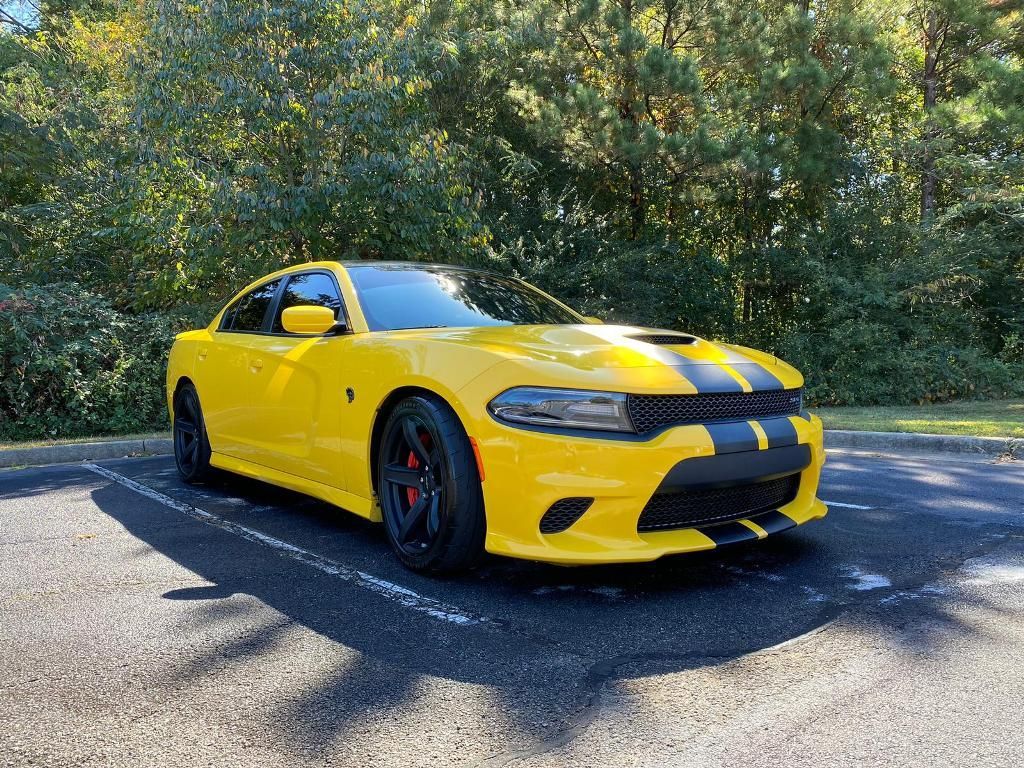 A yellow dodge charger is parked in a parking lot.