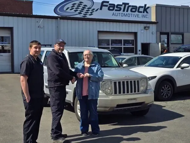 A group of people shaking hands in front of a fastrack automotive inc. building - FasTrack Automotive, Inc.