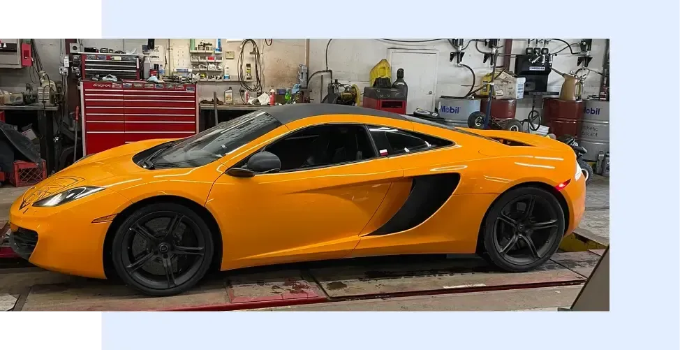 A yellow sports car is parked in a garage - FasTrack Automotive, Inc.