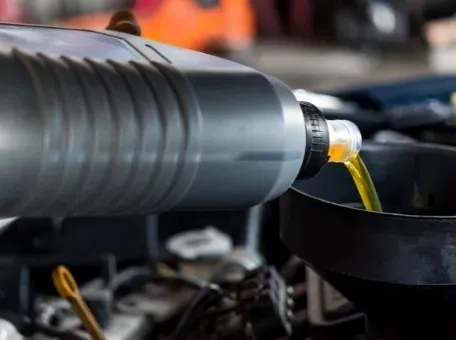 A person is pouring oil into a car engine - FasTrack Automotive, Inc.