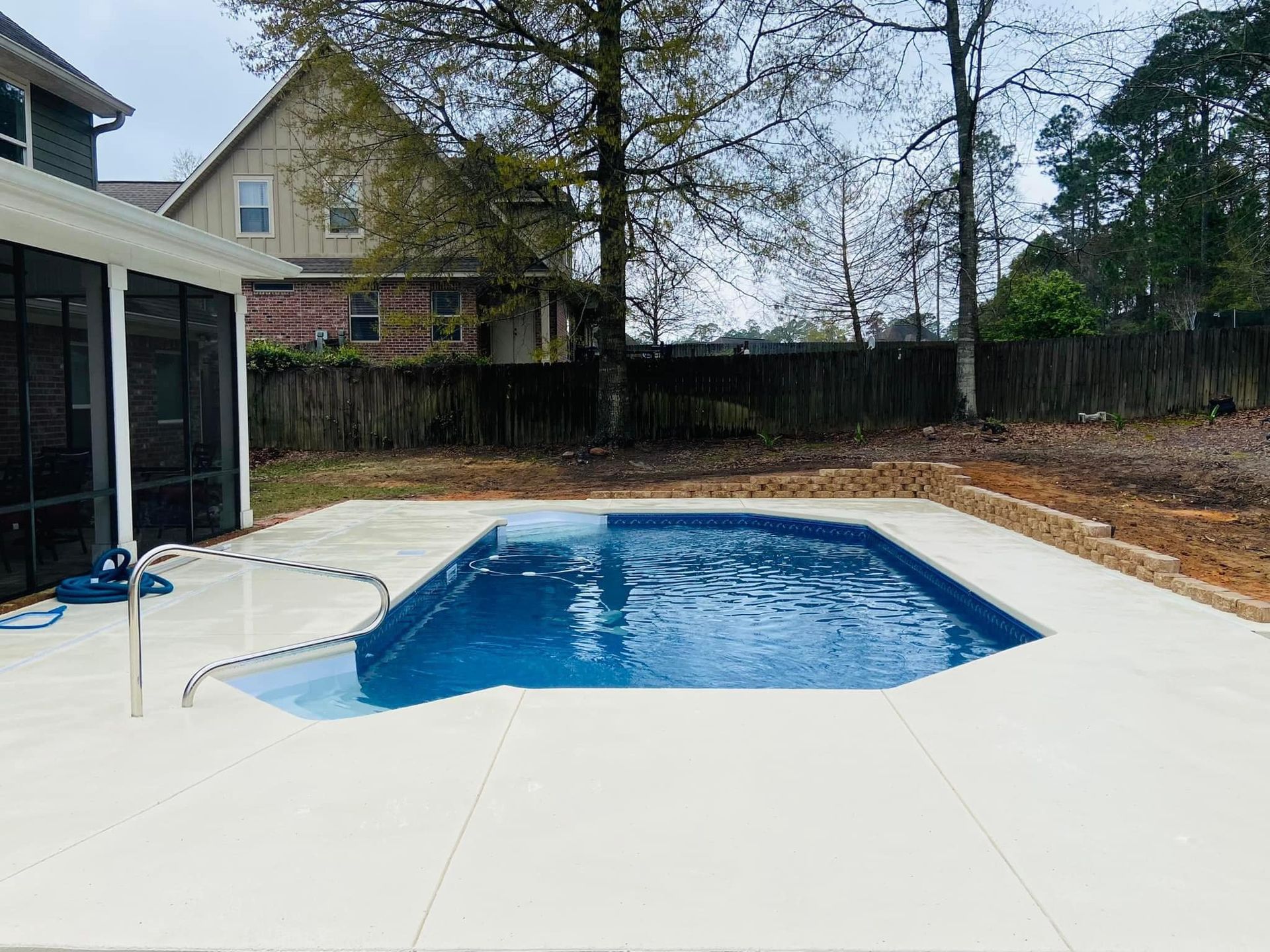A large swimming pool is in the backyard of a house.
