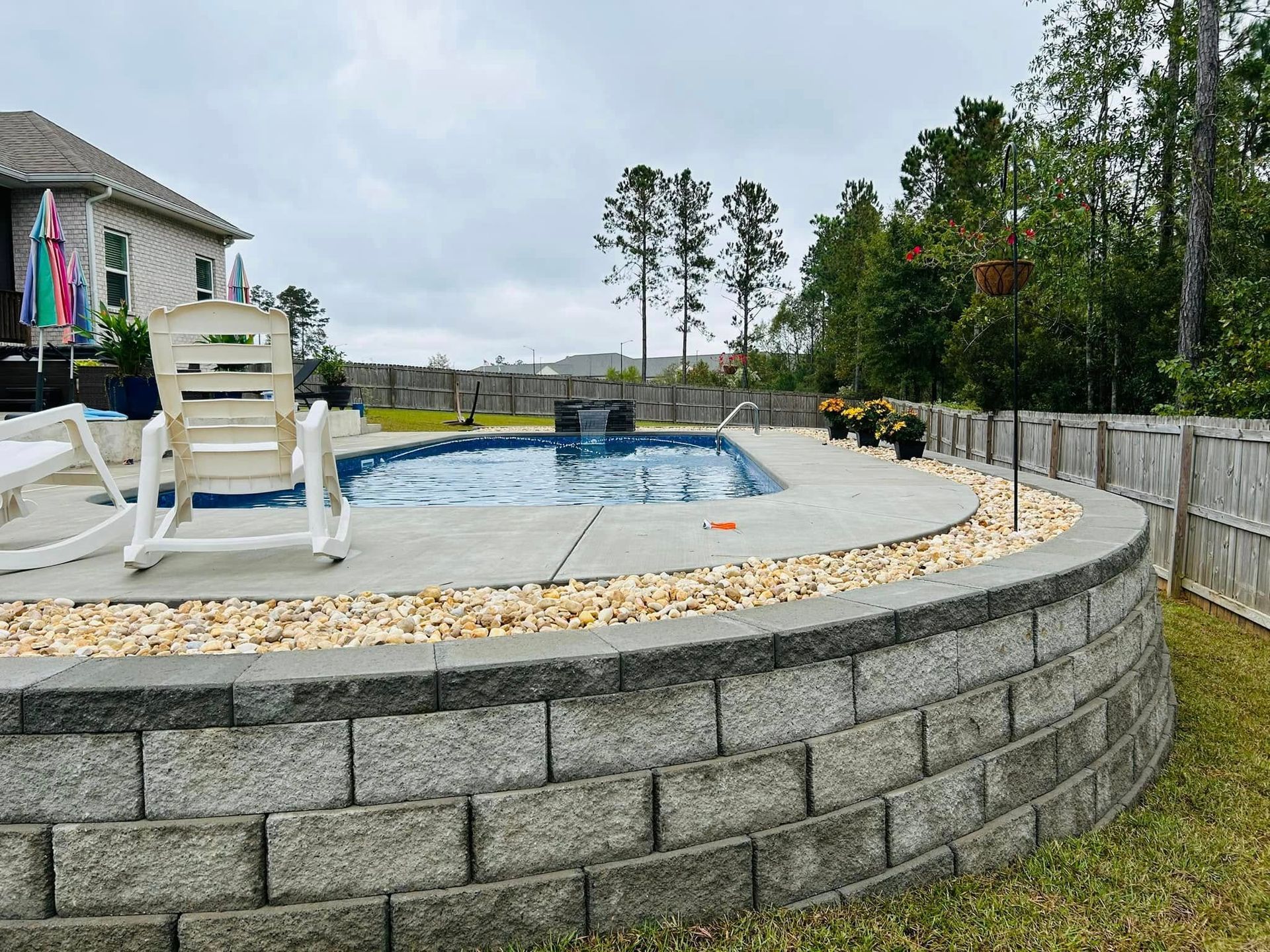 A rocking chair is sitting next to a swimming pool in a backyard.