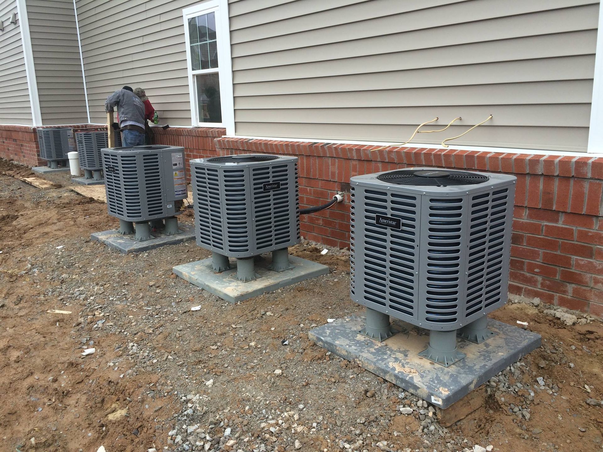 Air conditioning units outside a building with a worker.
