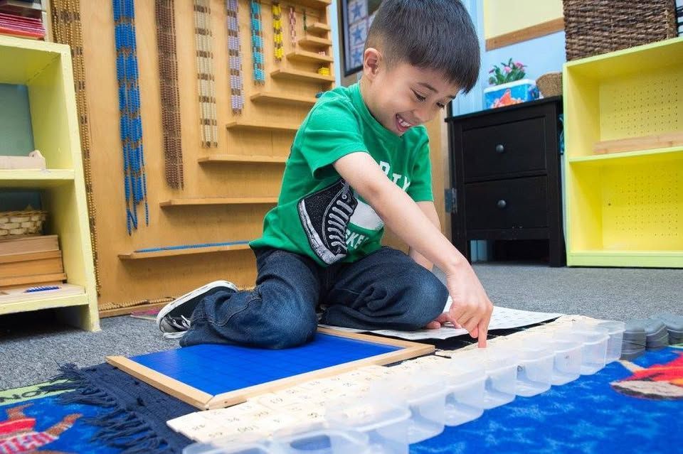 A young boy is kneeling on the floor playing with toys.
