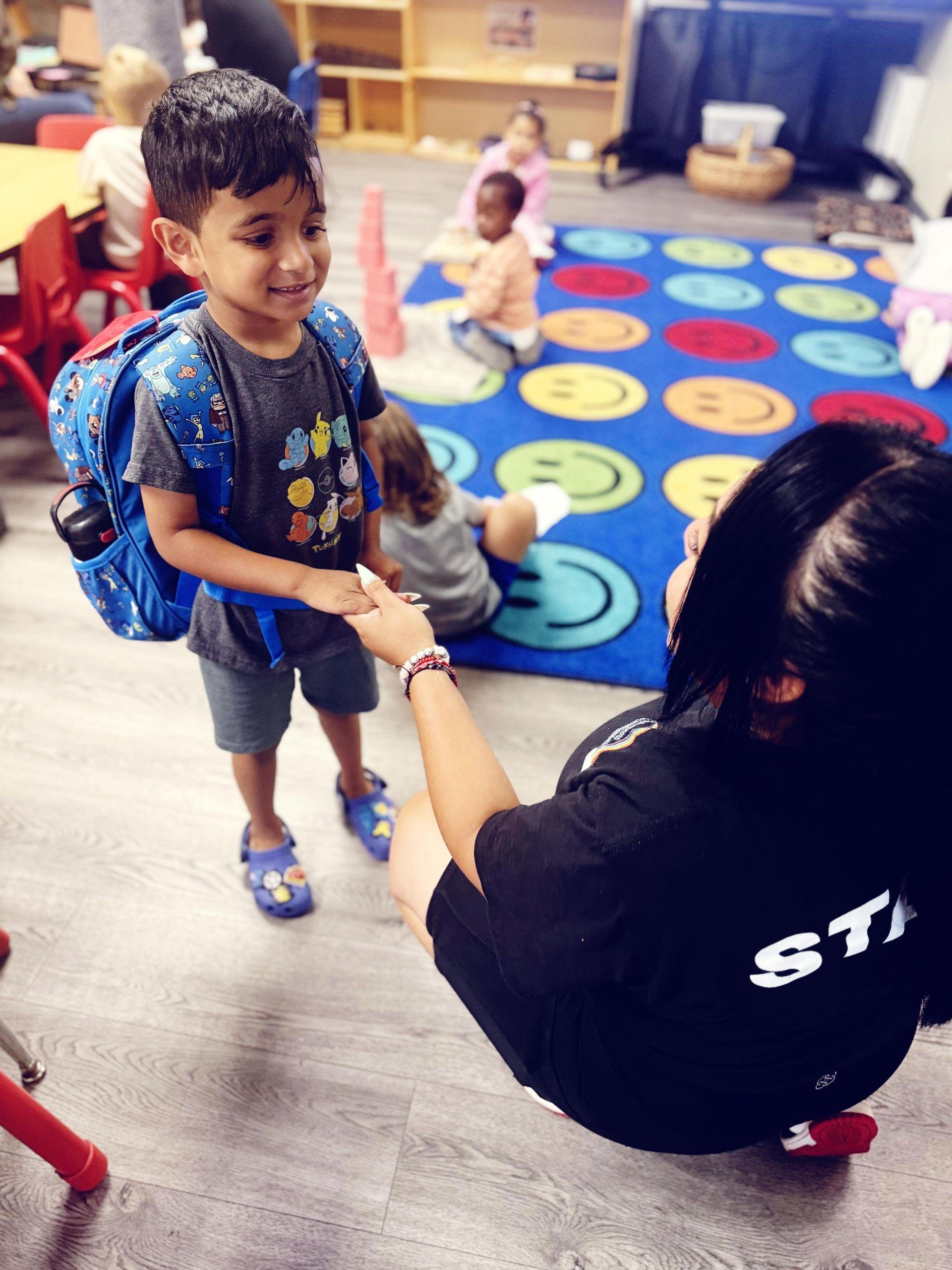 A young boy is kneeling on the floor playing with toys.