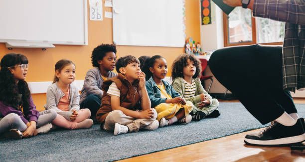 A group of children are sitting on the floor listening to a story.