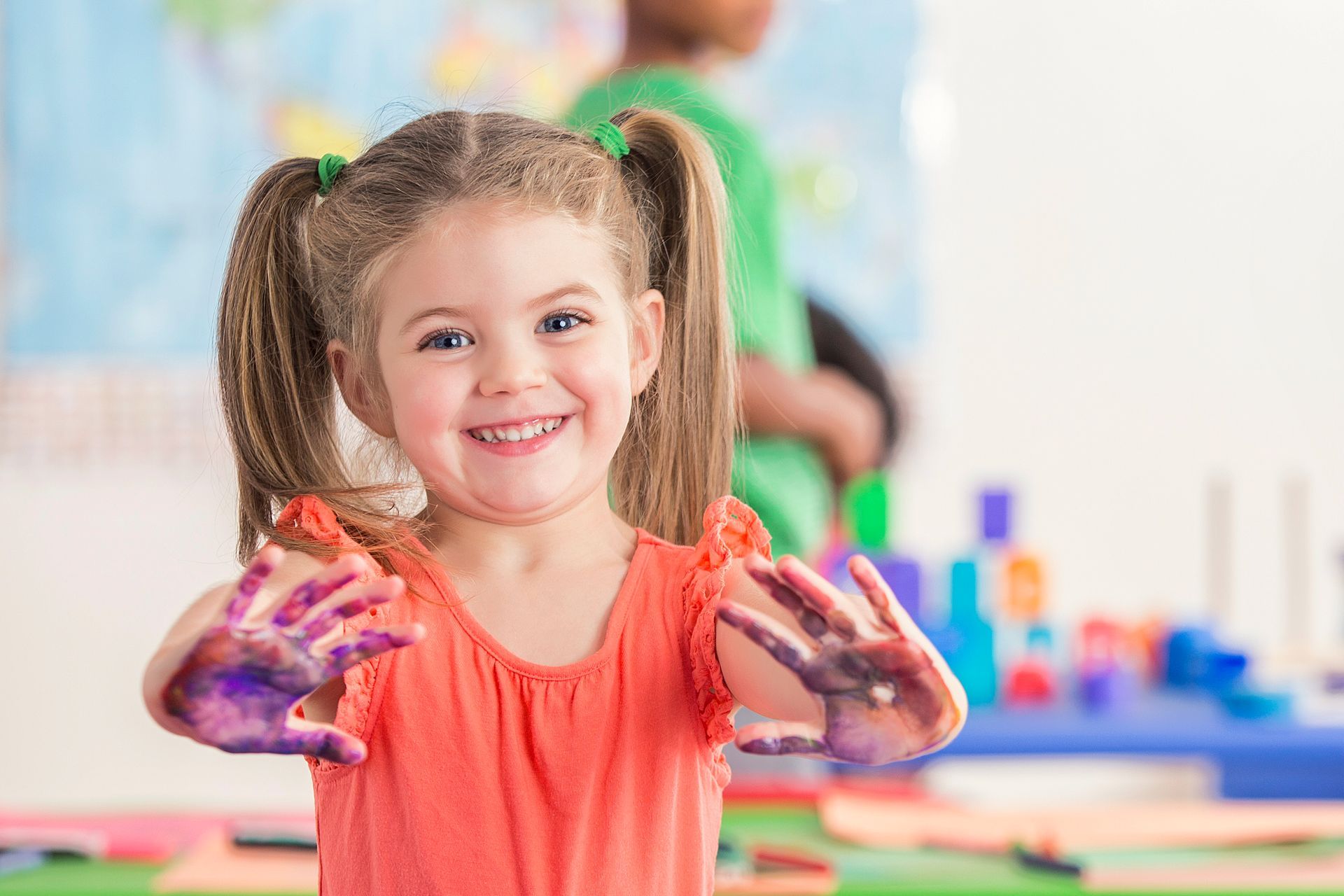 A little girl with her hands covered in paint.