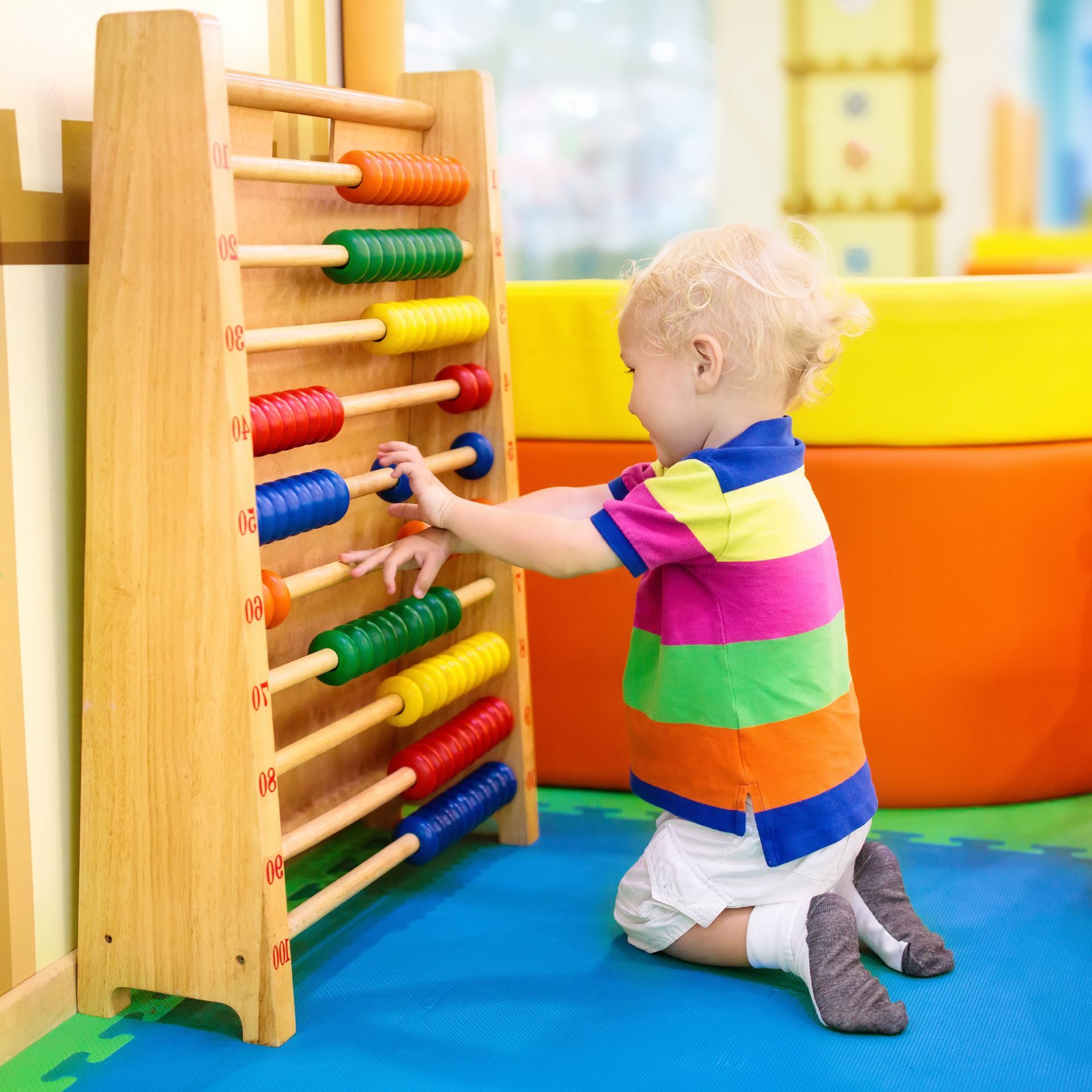 A little boy is playing with a wooden abacus