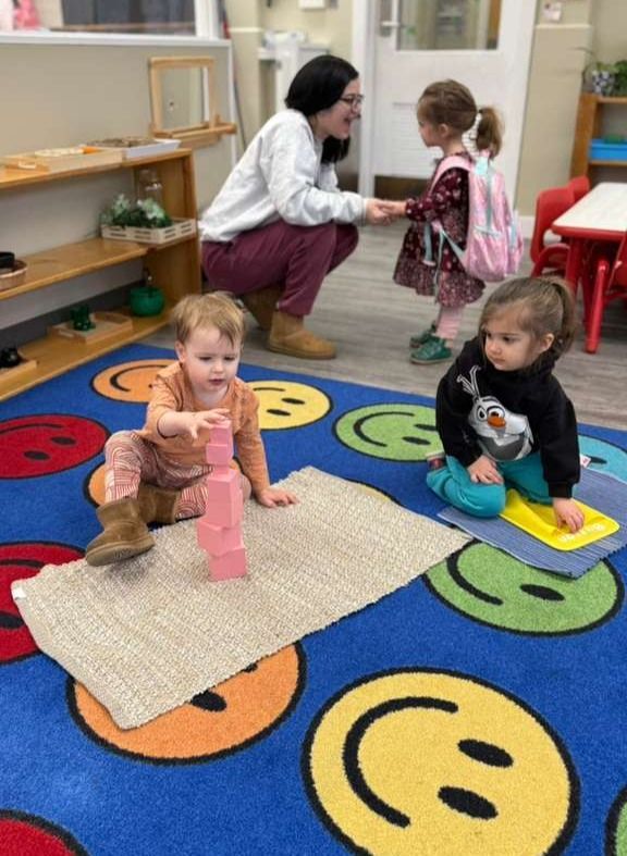 A young boy is kneeling on the floor playing with toys.