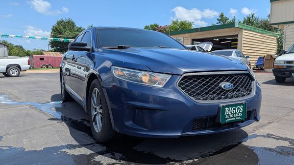 Blue Ford Taurus car parked on a paved lot in front of a building with a