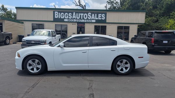 White Dodge Charger parked outside Biggs Auto Sales building.