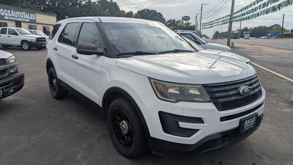 White Ford Explorer police SUV parked in front of a car dealership.