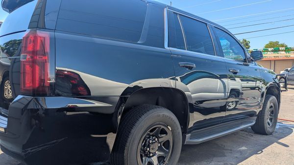 Black SUV parked on a sunny day, with reflections of other vehicles.