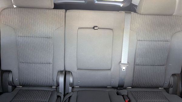 Car's back seats: gray fabric, middle seat has fold-down armrest, seatbelts visible.