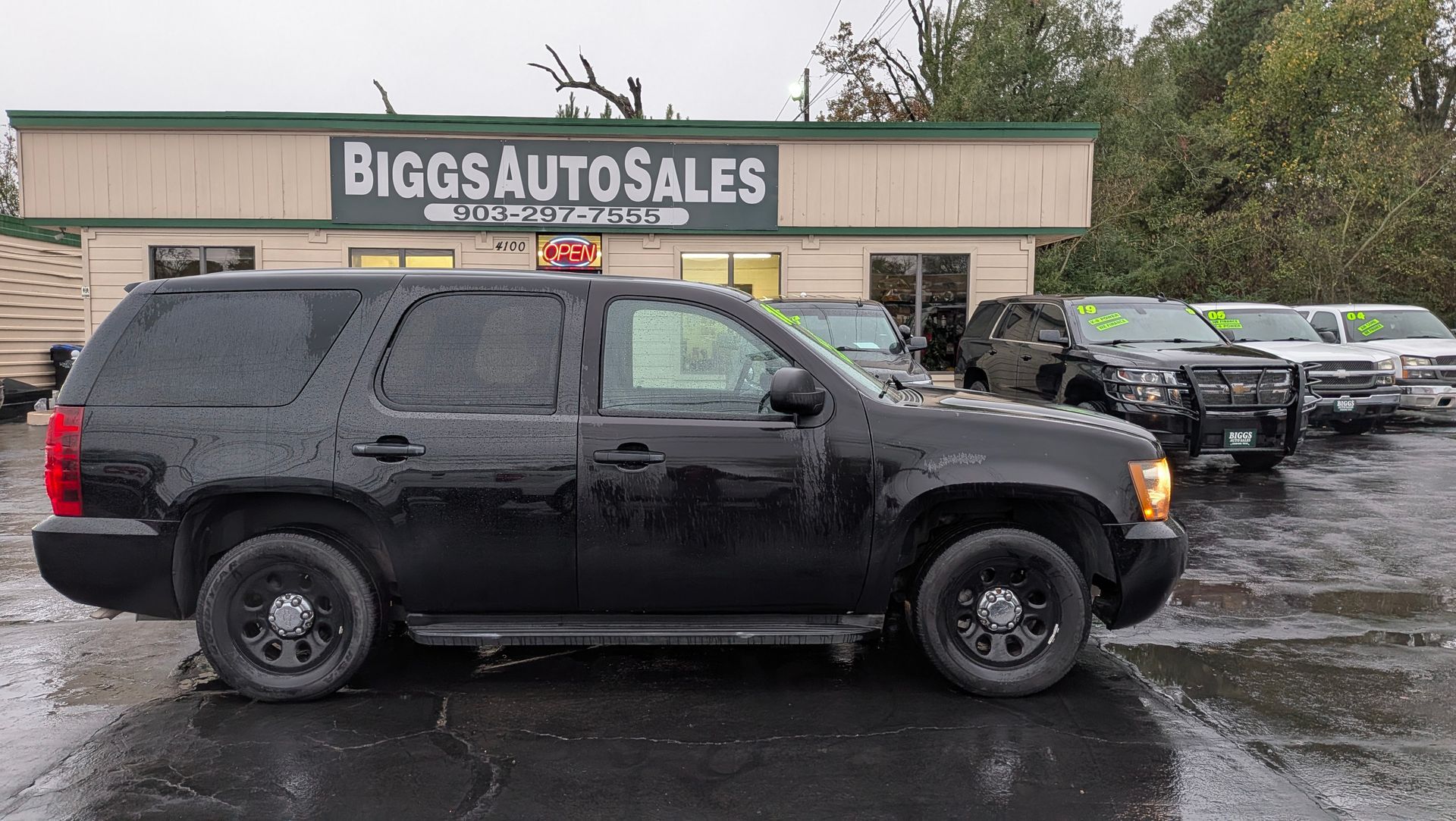 Black SUV parked in front of Biggs Auto Sales, other vehicles in the background.