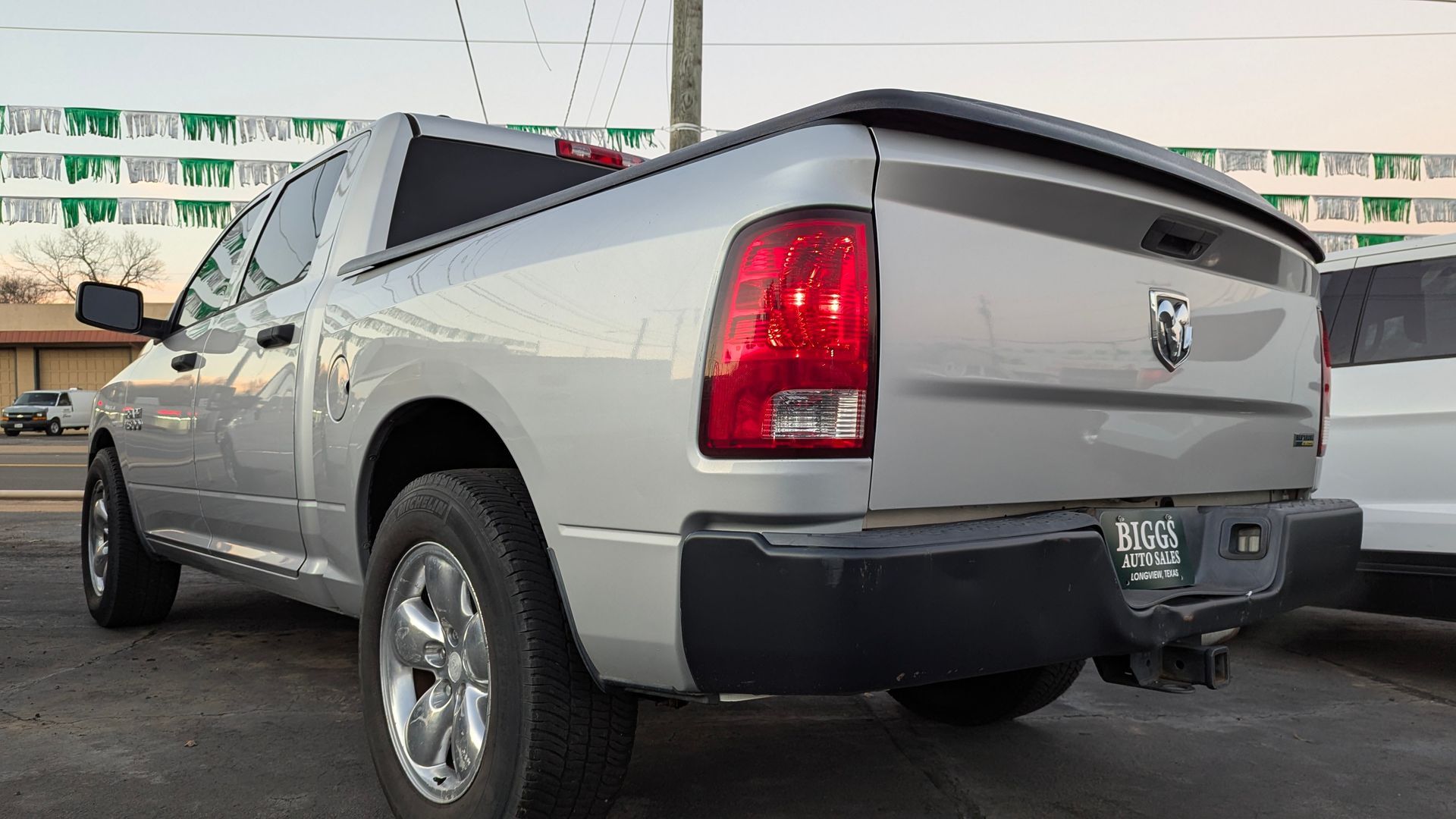Silver Ram pickup truck parked outside, rear view. Black bumper, taillight, and license plate.