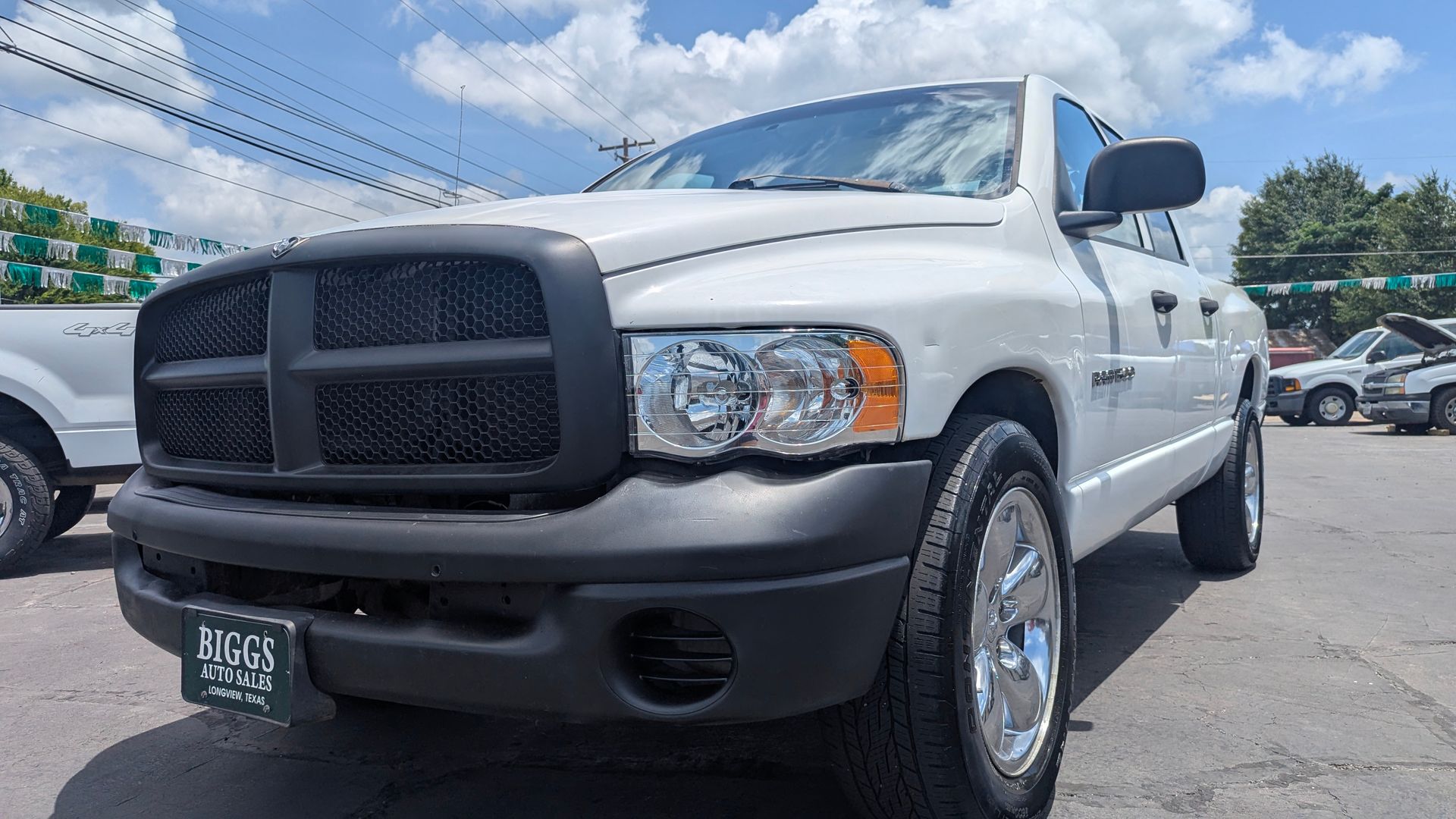 White Dodge Ram truck with black grill and bumper parked outside on a sunny day.