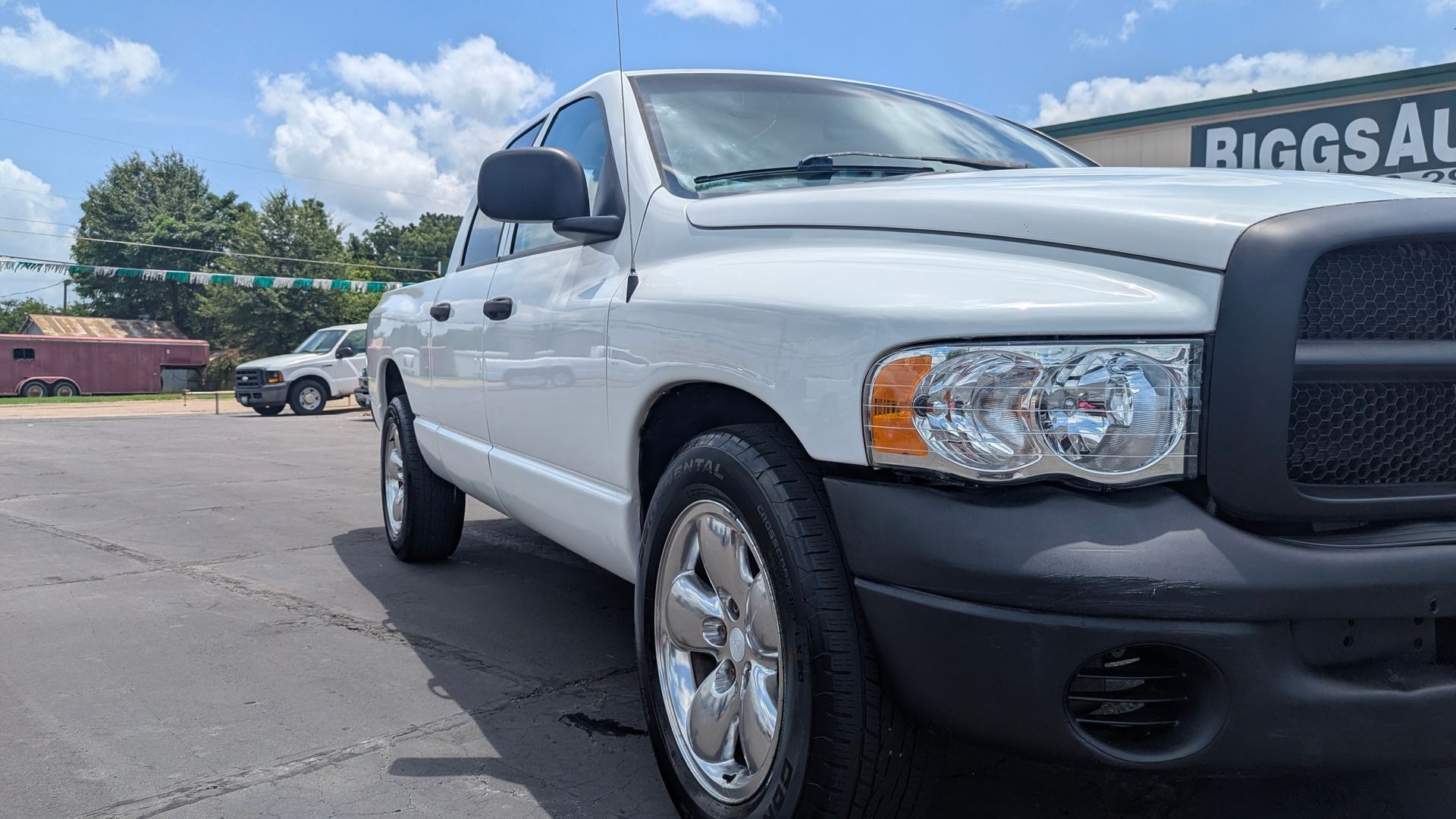 White Dodge Ram pickup truck parked outside a business under a blue sky.