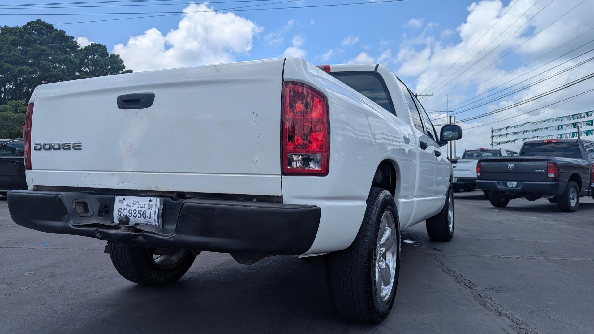 White Dodge Ram pickup truck parked on asphalt with other vehicles in the background.