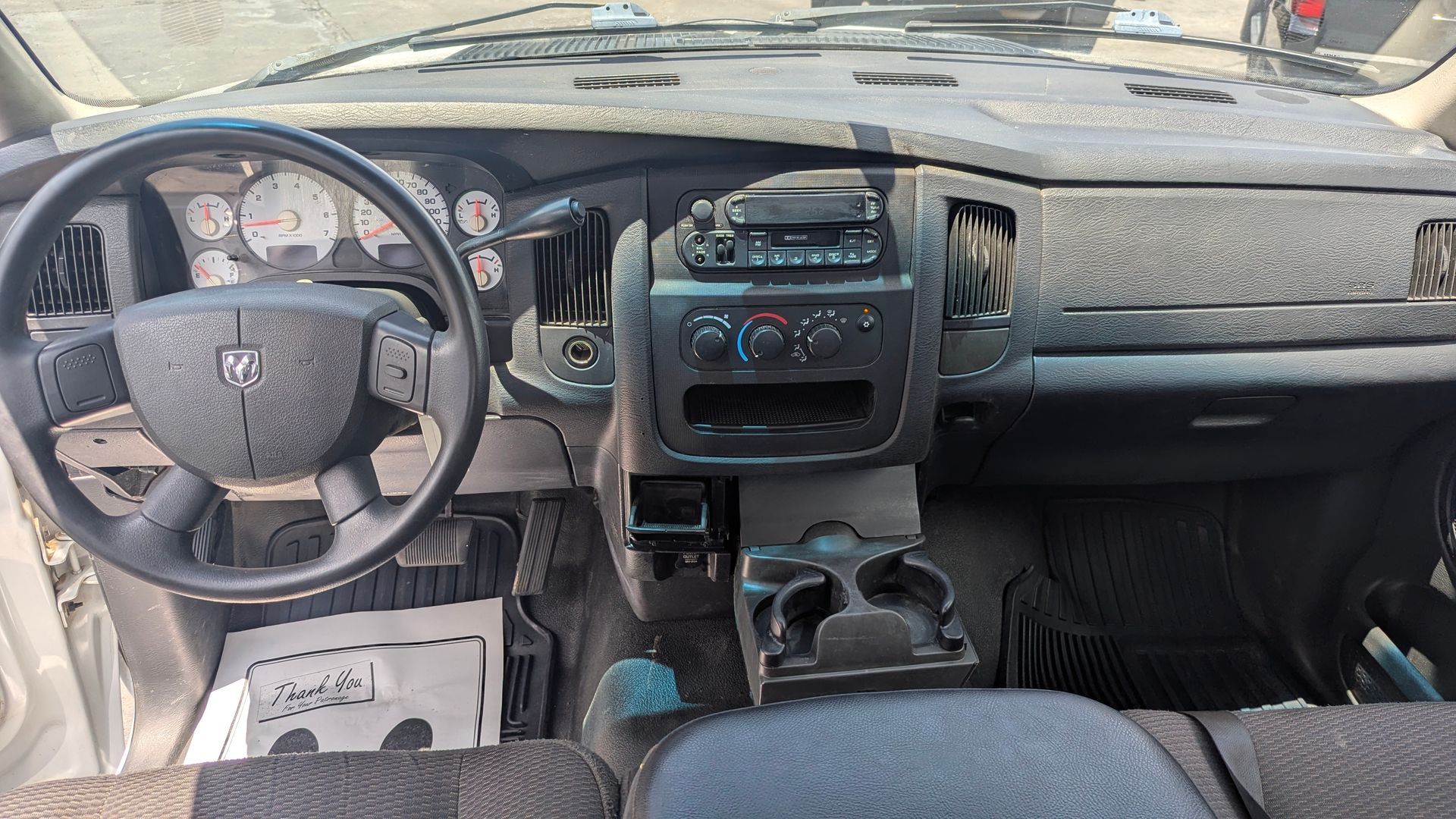 Dashboard of a Dodge Ram truck, featuring steering wheel, gauges, radio, and cup holders.