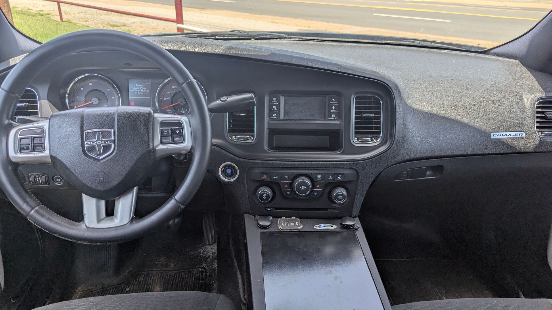 Dashboard of a black Dodge Charger police car, featuring the steering wheel, gauges, and center console.