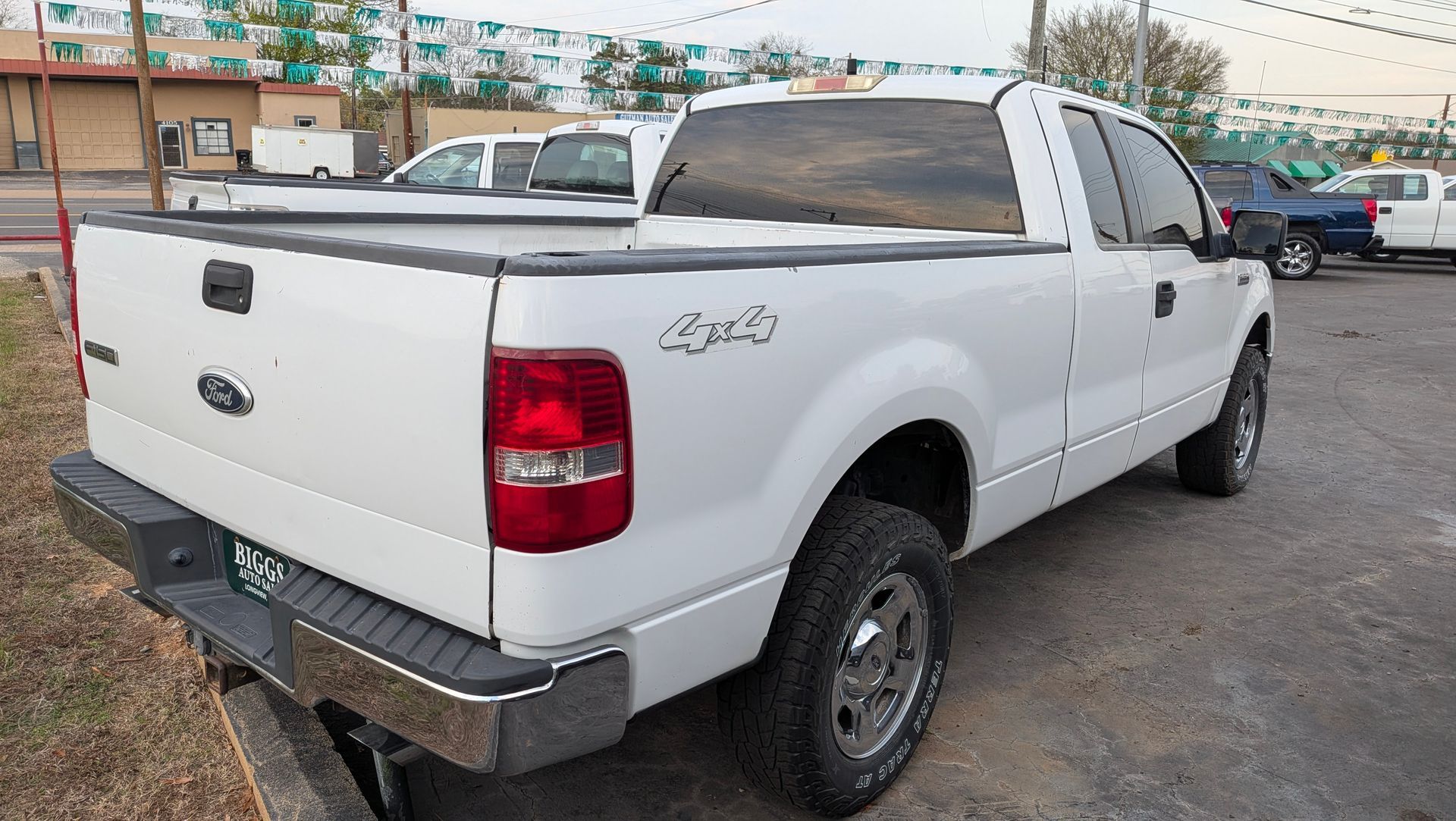 White Ford F-150 pickup truck parked outside. 4x4 emblem on the rear, chrome bumper and wheels.