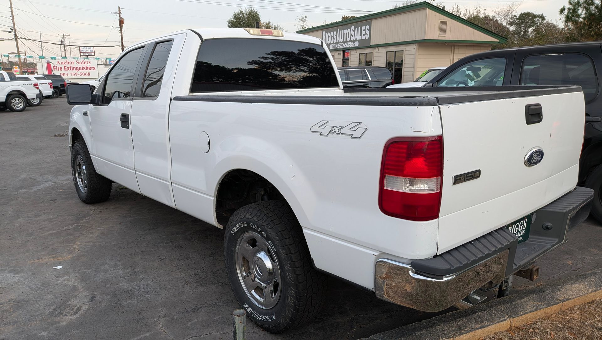 White Ford F-150 pickup truck parked outside a business, with a 4x4 emblem.