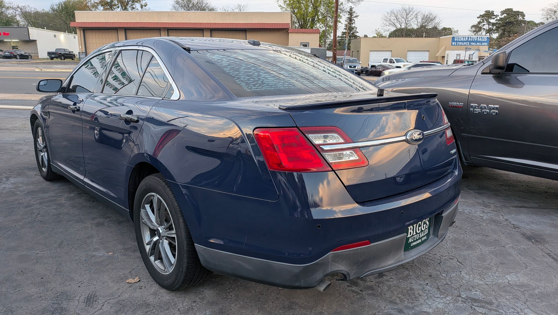 Blue sedan parked outside. Chrome rims, taillights, and spoiler visible.
