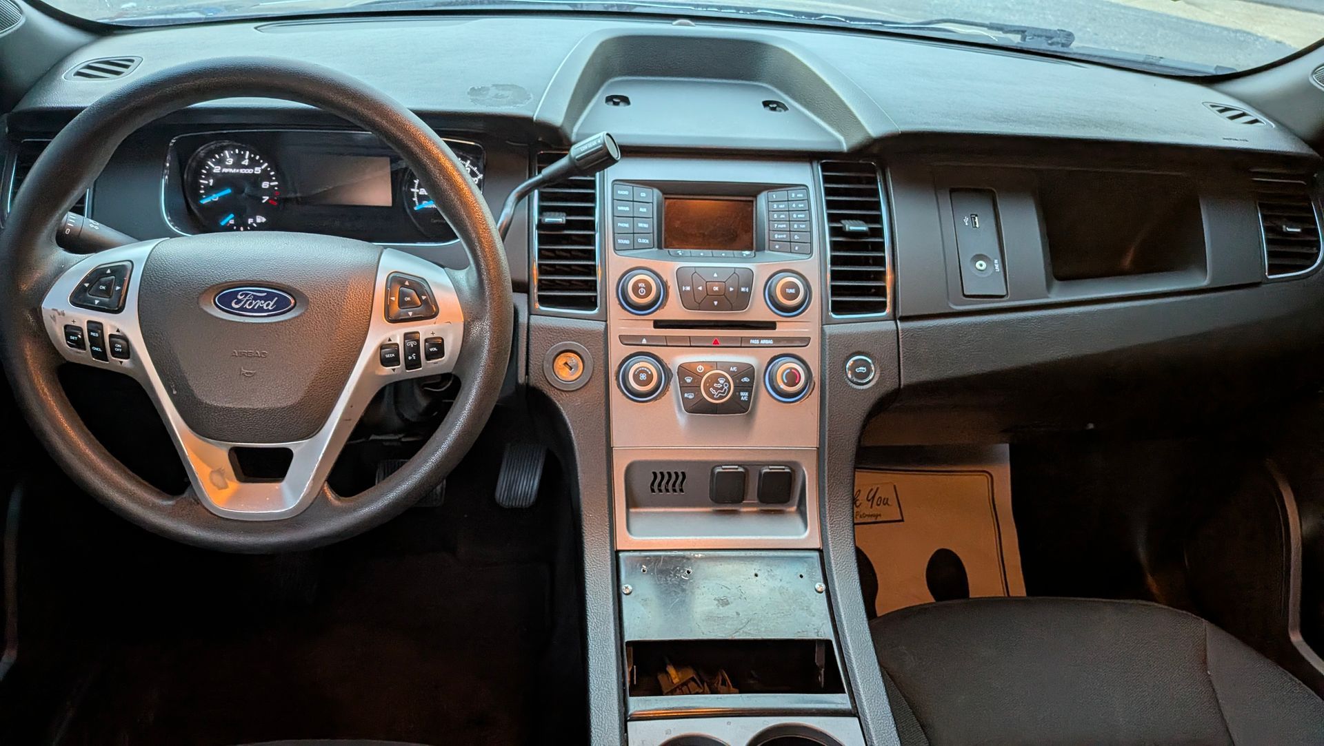 Car interior showing dashboard with steering wheel, gauges, and center console.