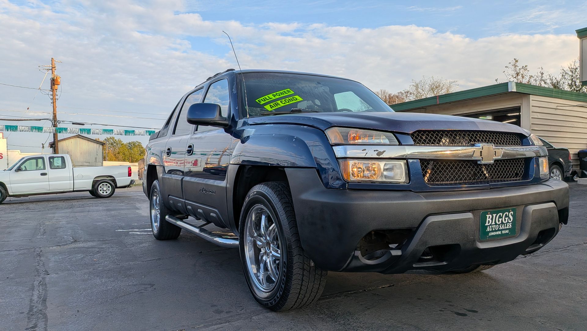 Dark blue Chevrolet Avalanche truck parked outside a dealership.